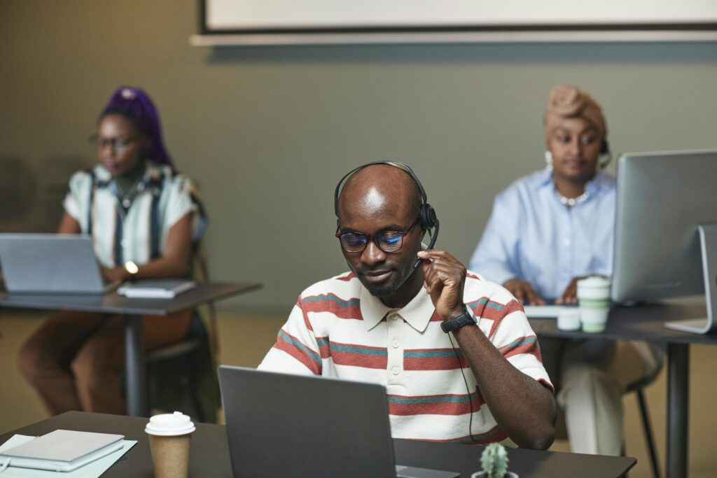 A focused call center team working on laptops and wearing headsets in an office setting.